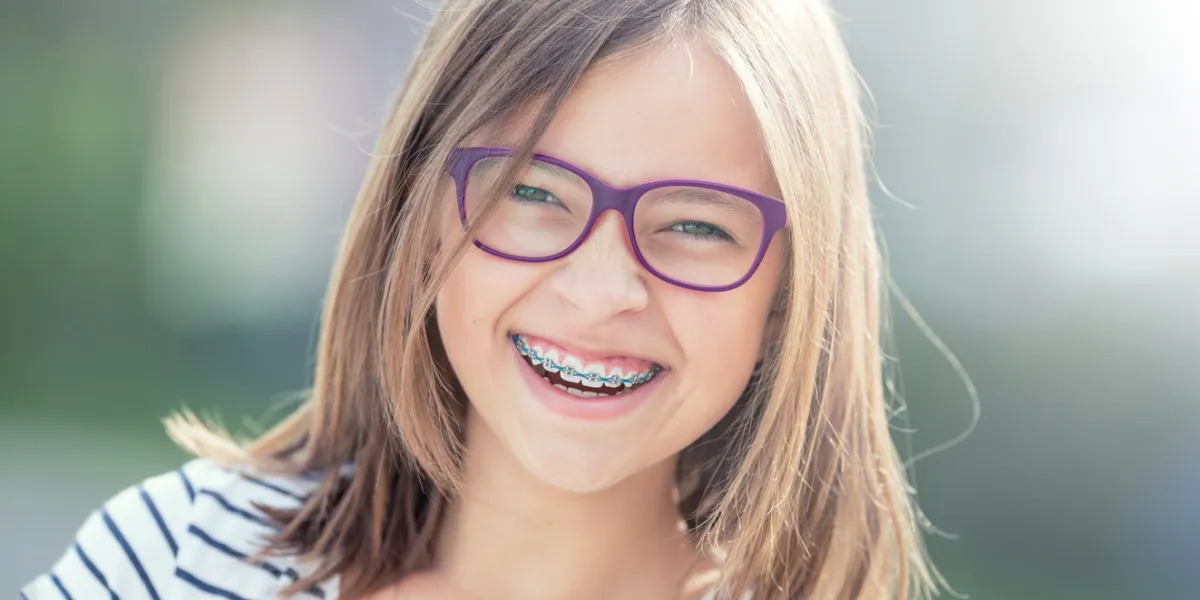 portrait of happy smiling girl with dental braces and glasses