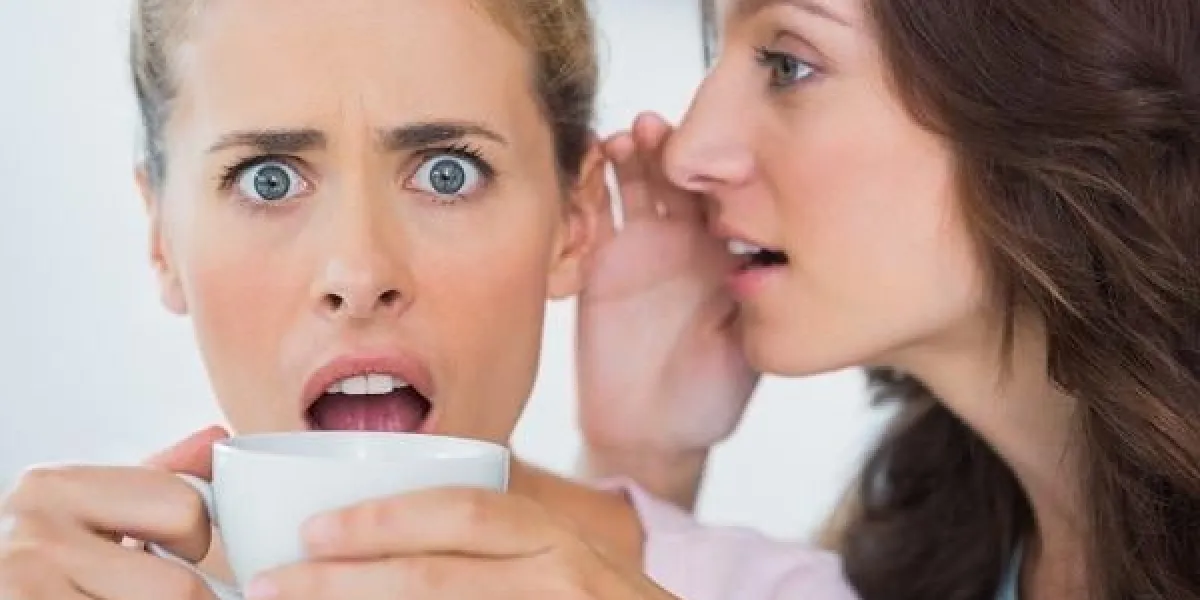 woman telling secret to her friend and astonishing her while drinking coffee