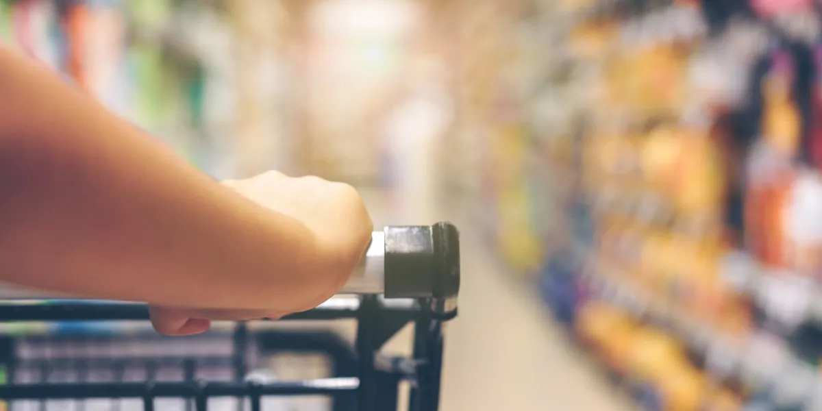 asian woman's hand with supermarket, trolley and many objects that are blurred background