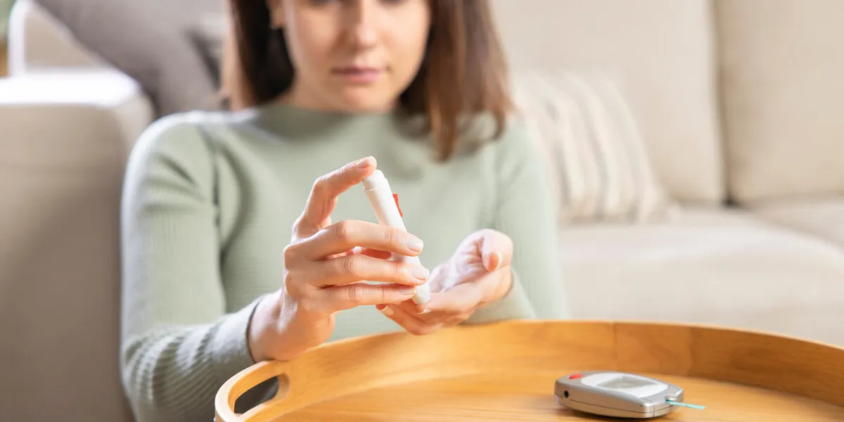 woman using lancet on finger to check blood sugar level by glucose meter medicine, diabetes, glycemia and health care concept woman using lancet on finger to check blood sugar level by glucose meter medicine, diabetes, glycemia and health care concept