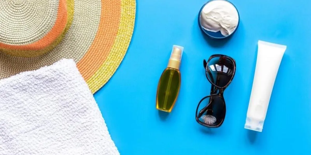 towel, sun lotion, glasses for summer rest on blue background top view