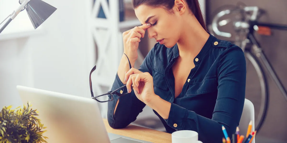 jeune femme frustrée, gardant les yeux fermés et massant le nez tout en étant assise à son lieu de travail au bureau jeune femme frustrée, gardant les yeux fermés et massant le nez tout en étant assise à son lieu de travail au bureau