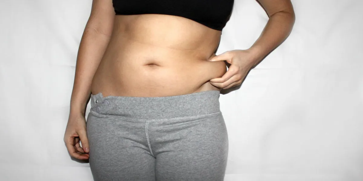 torso of young woman, which holding a belly fat in fingers overweight, weight loss, christmass food kilograms, dissatisfaction with own body concept torso of young woman, which holding a belly fat in fingers overweight, weight loss, christmass food kilograms, dissatisfaction with own body concept