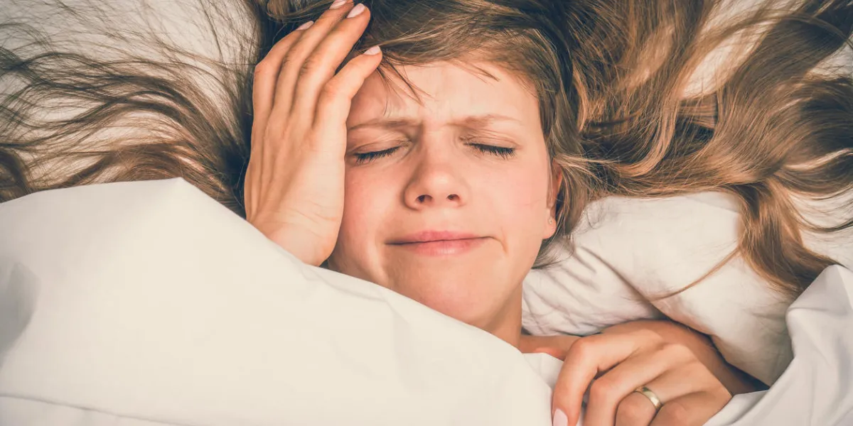 young woman in bed having headache in the morning