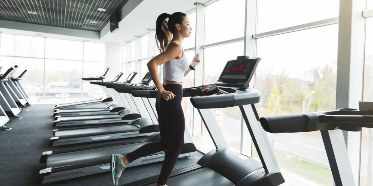 sports woman training on treadmill near the window in gym