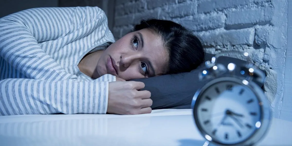 jeune belle femme hispanique à la maison chambre coucher dans son lit tard dans la nuit, essayant de dormir souffrant d'insomnie trouble du sommeil ou effrayé sur les cauchemars à la recherche triste inquiet et stressé