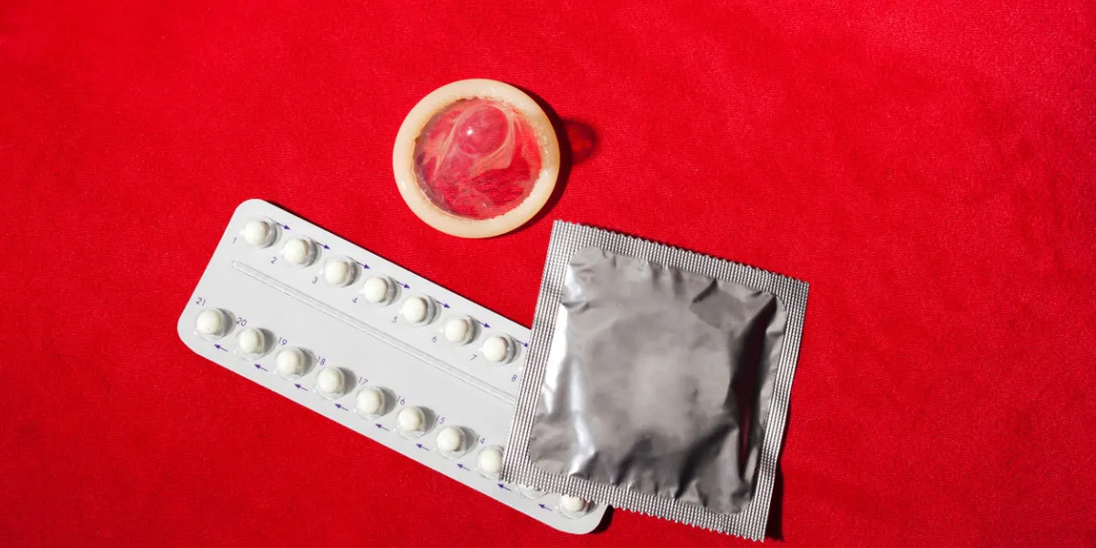 birth control pills and condoms, isolated on red background birth control pills and condoms, isolated on red background