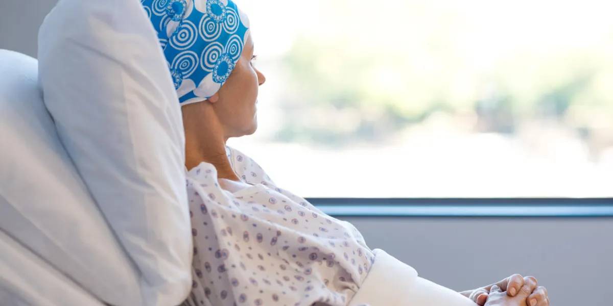 young woman in bed suffering from cancer thoughtful woman battling with tumor looking out of window young patient with blue headscarf recovery in hospital on bed young woman in bed suffering from cancer thoughtful woman battling with tumor looking out of window young patient with blue headscarf recovery in hospital on bed