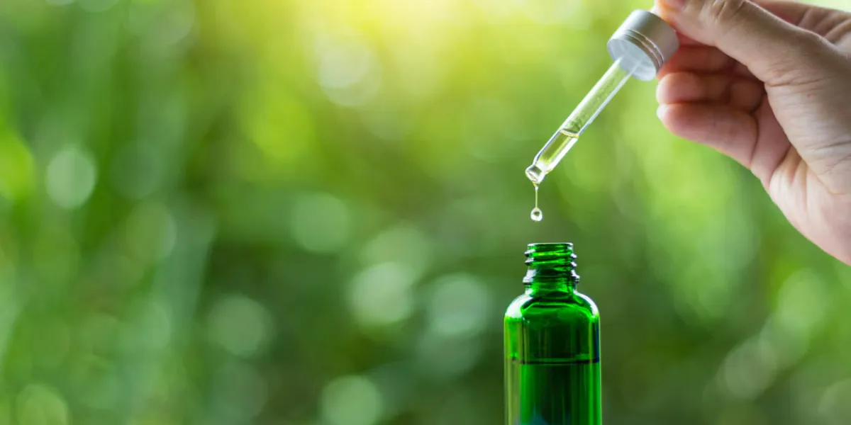 woman’s hand holding pipette , essential liquid falling into glass woman’s hand holding pipette , essential liquid falling into glass