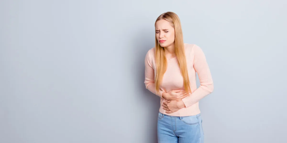 portrait of sad unhappy upset stressed frustrated depressed crying troubled nervous bad negative feeling woman touching holding tummy with hands isolated on gray background copy-space