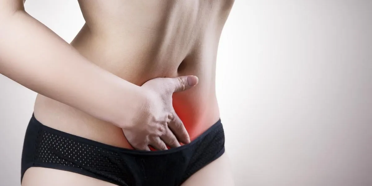 woman with abdominal pain pain in the human body on a gray background with red dot