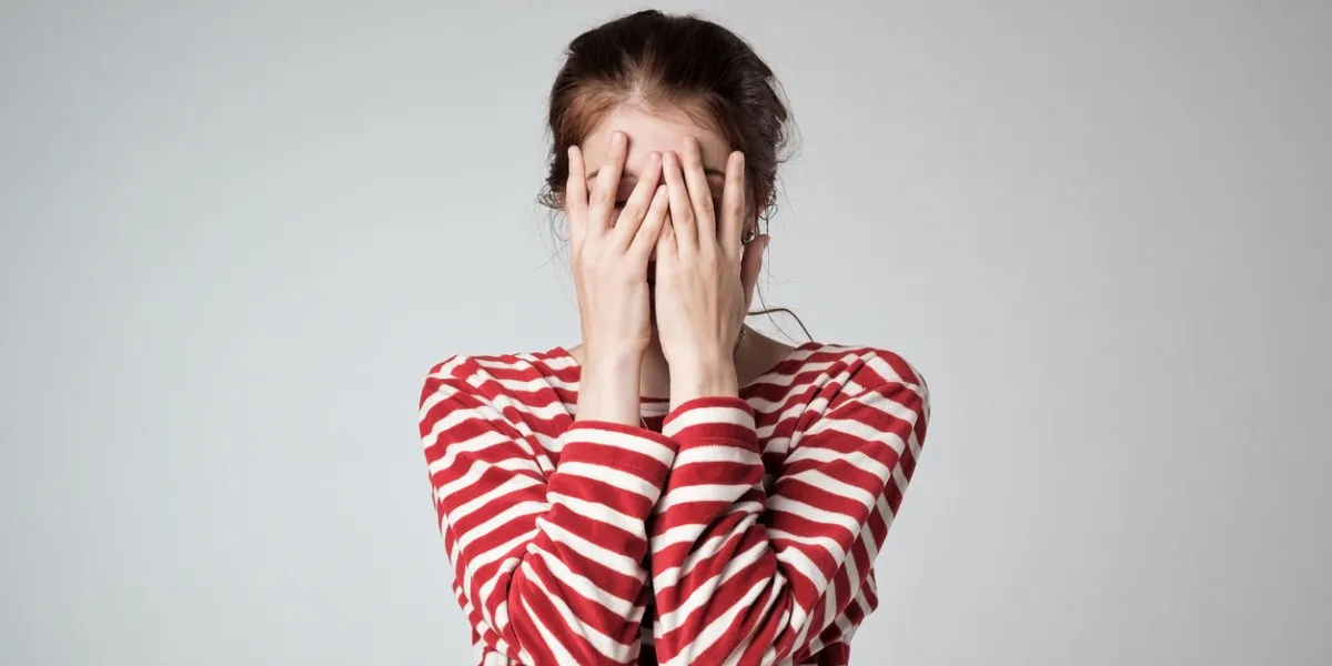 pretty caucasian girl covers her face with her hands, feel embarrassed or shy