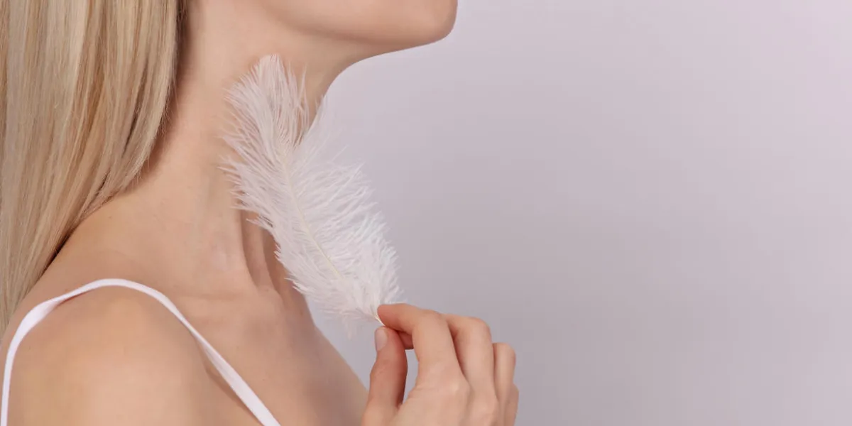 attractive young woman touching her smooth perfect skin after beauty treatment with feather woman thyroid gland control health care and medical concept