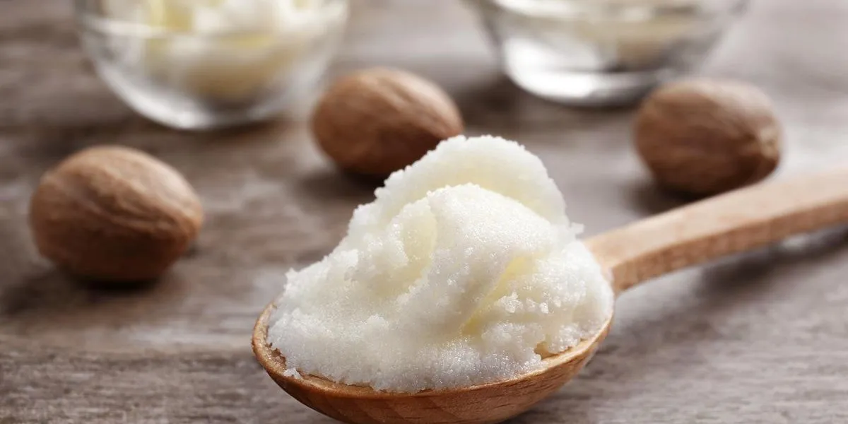 shea butter in spoon and bowls on wooden background, close up