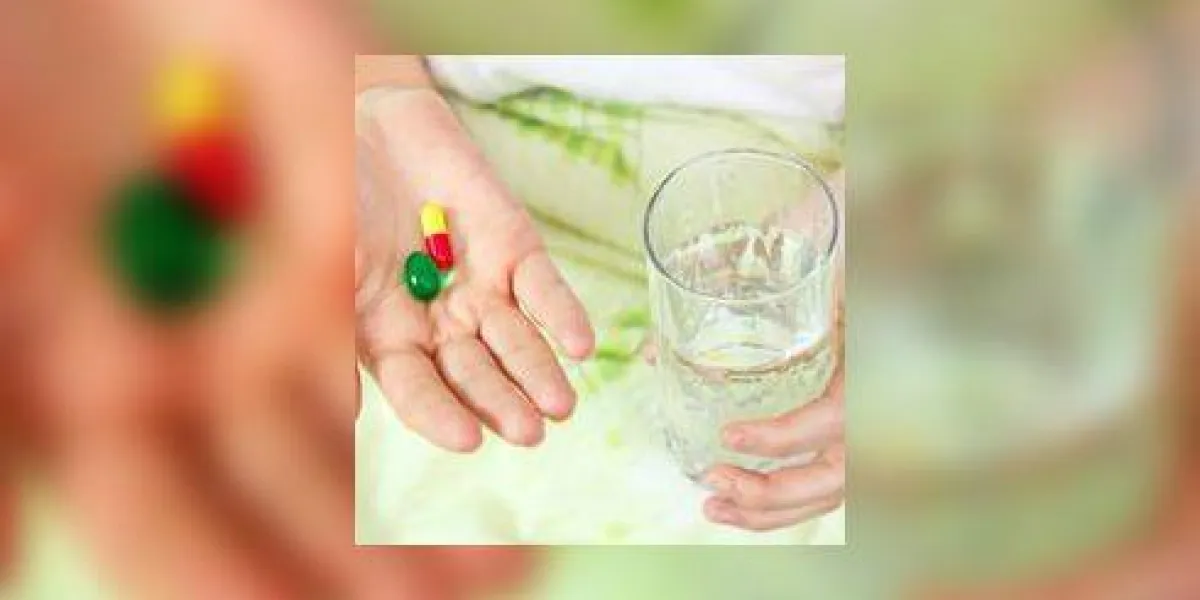 femme tenant deux pilules et un verre d'eau