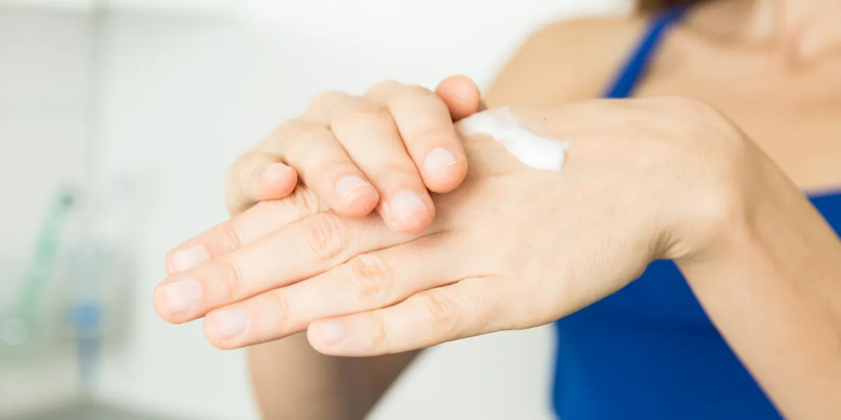 female hands using hand lotion because of dry hands