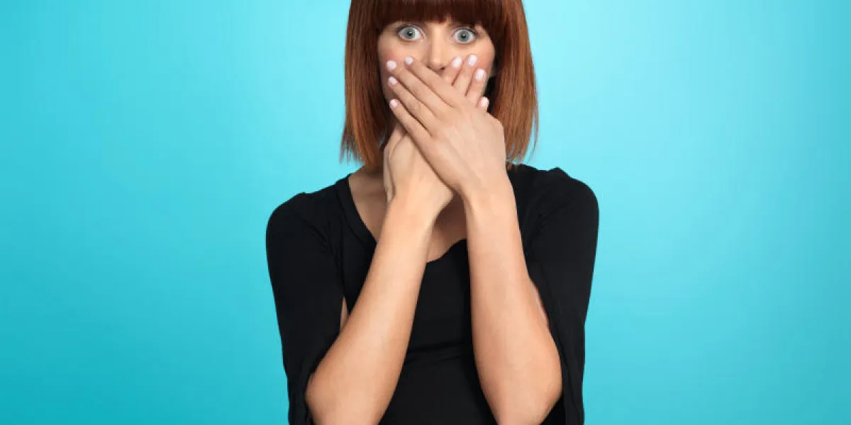 belle, jeune femme, avec une expression de visage surpris, couvrant sa bouche, sur fond bleu