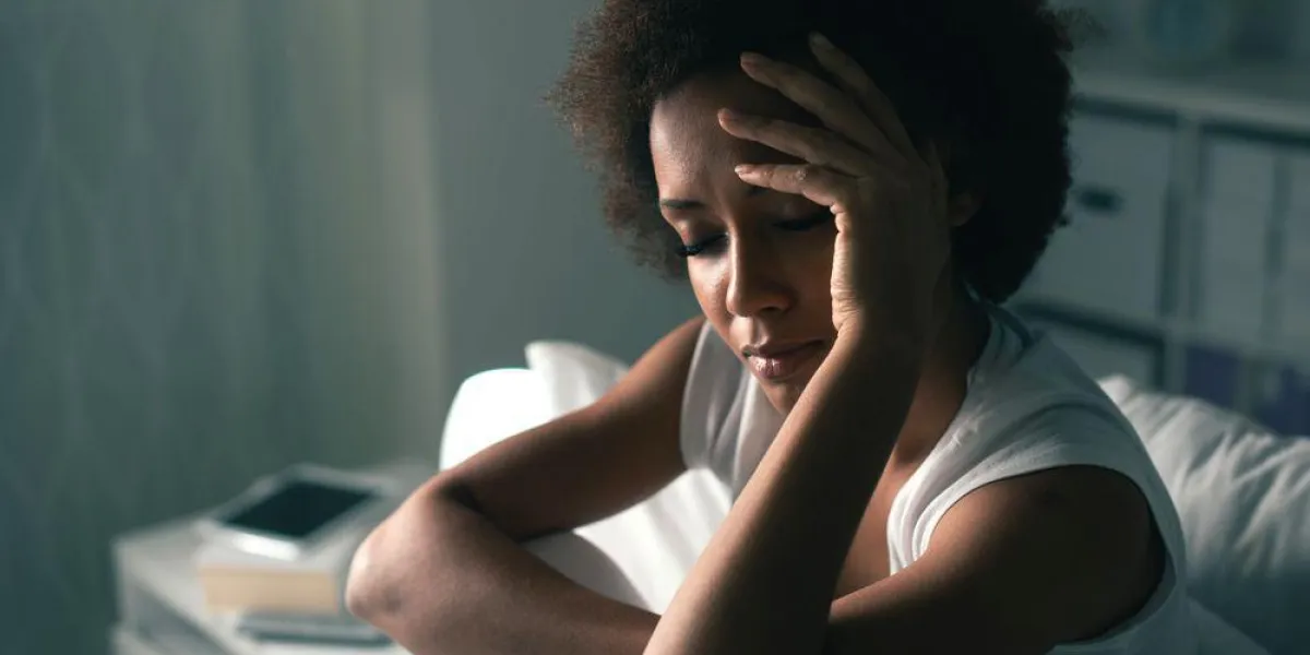 triste femme déprimée souffrant d'insomnie, elle est assise dans son lit et de toucher son front, le trouble du sommeil et le concept de stress