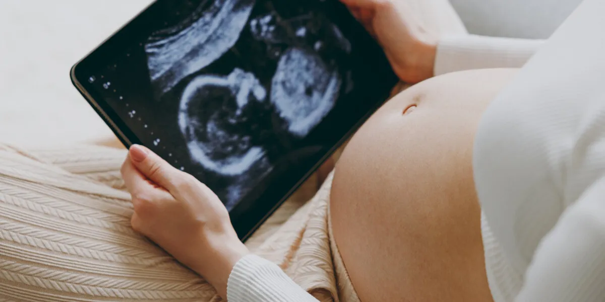 cropped close up young pregnant woman wears white pyjamas hold in hand picture of ultrasound examination rest relax spend time in bedroom lounge home maternity family pregnancy expectation concept