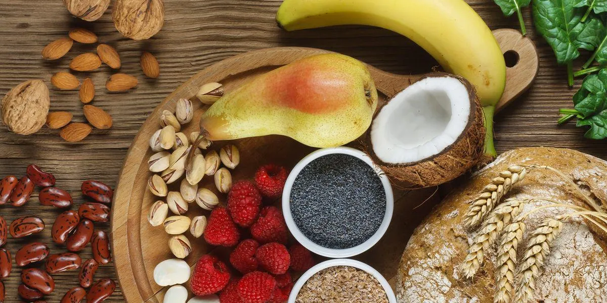 aliments riches en fibres comme pain de seigle, son de blé, haricots blancs, haricots rouges, épinards, amandes, graines de pavot, poires, bananes, noix de coco, framboises, pistaches, noix table en bois en arrière-plan aliments riches en fibres comme pain de seigle, son de blé, haricots blancs, haricots rouges, épinards, amandes, graines de pavot, poires, bananes, noix de coco, framboises, pistaches, noix table en bois en arrière-plan