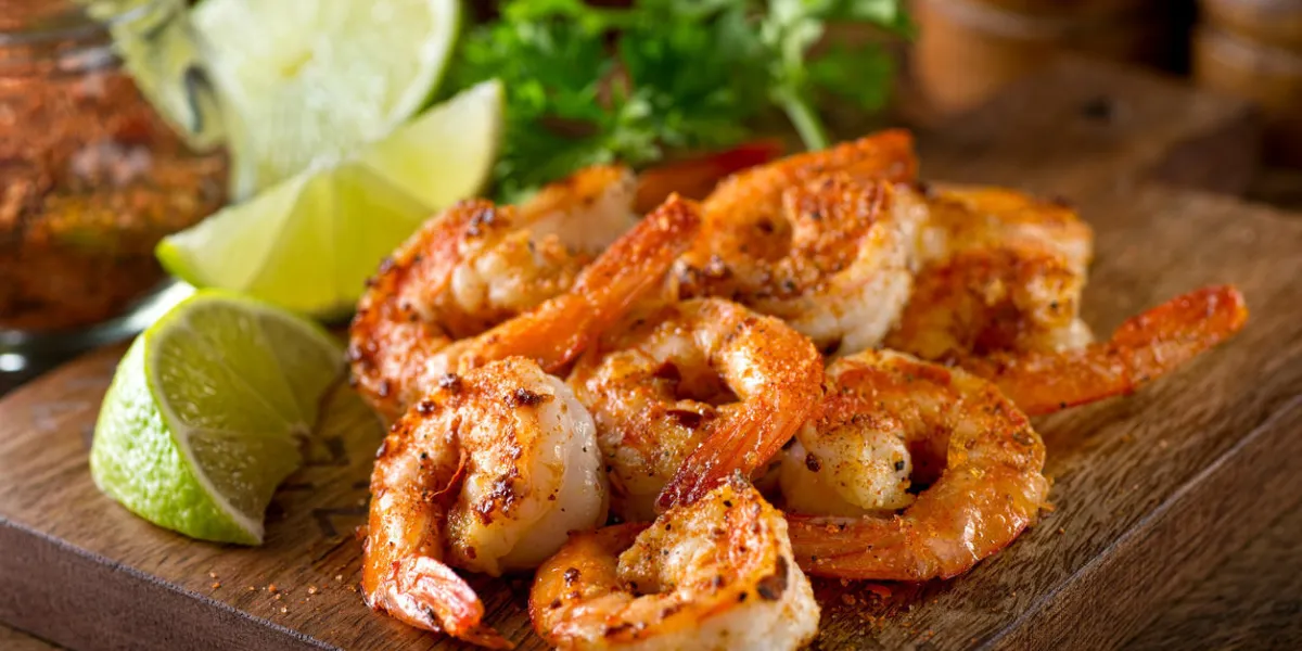 délicieuses crevettes sautées avec assaisonnement cajun et citron vert sur une planche d'érable