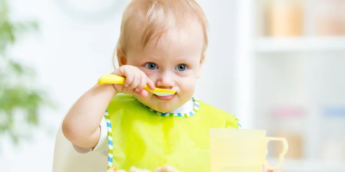 happy baby child sitting in chair with a spoon happy baby child sitting in chair with a spoon