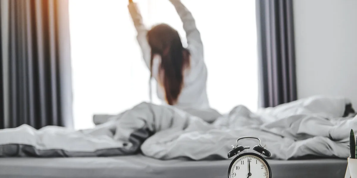 asian woman wake up on bed stretching feeling happy and fresh enjoying in the morning