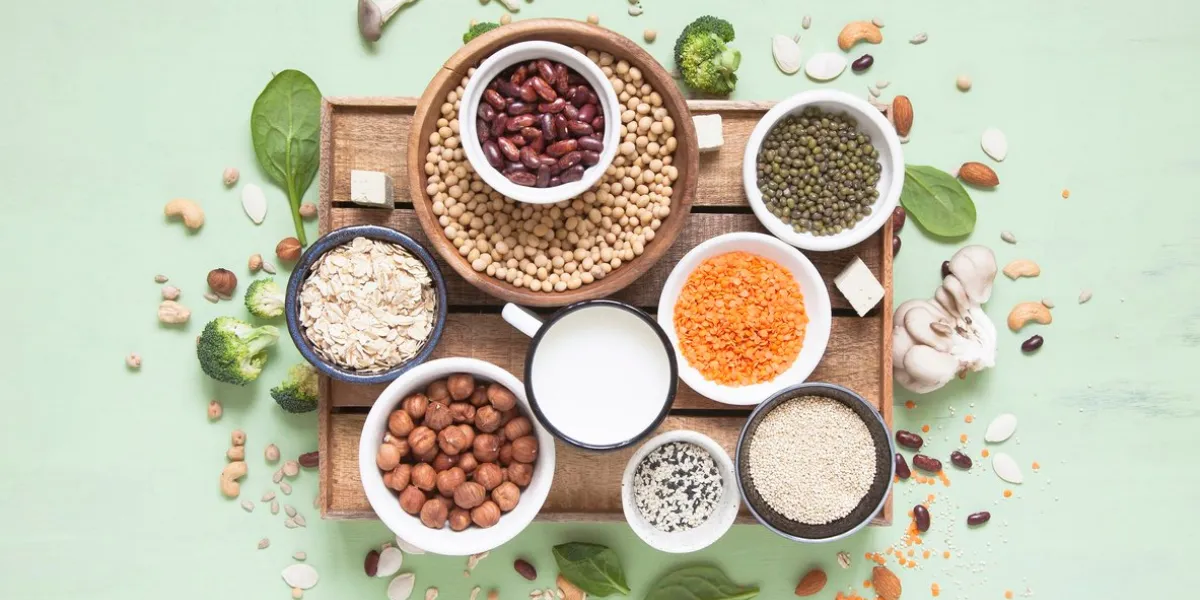 vegetable albumen sources plant protein (beans, nuts, vegetables, mushrooms, seeds) on green background vegan and vegetarian food concept flat lay