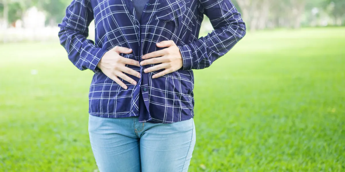 girl getting stomachache and pushing on abdomen while walking in park unrecognizable woman having indigestion because of malnutrition pain in stomache concept girl getting stomachache and pushing on abdomen while walking in park unrecognizable woman having indigestion because of malnutrition pain in stomache concept