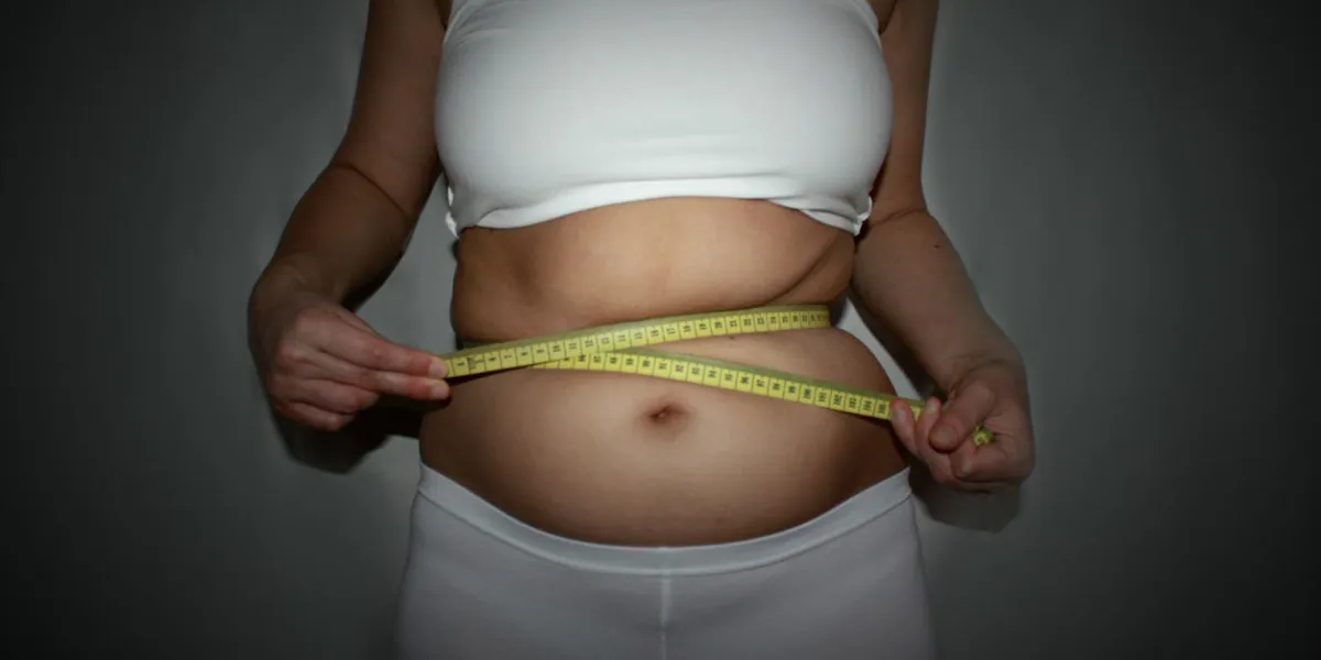 woman measuring waistline with centimeter tape dark vignette background horizontal photo of a woman, who wants lose weight woman measuring waistline with centimeter tape dark vignette background horizontal photo of a woman, who wants lose weight