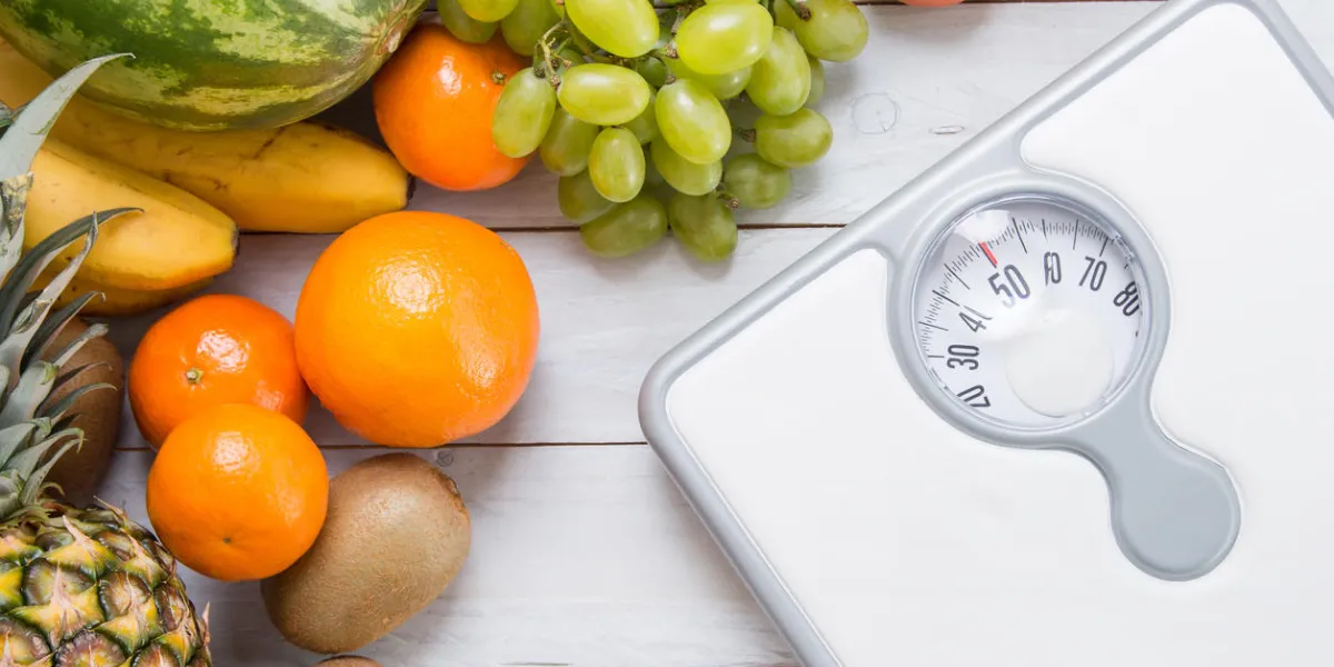 stack of fruits and white weight scale on wooden board concept of diet and healthy lifestyle stack of fruits and white weight scale on wooden board concept of diet and healthy lifestyle