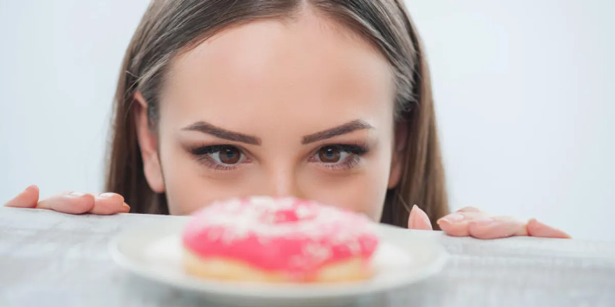 belle fille regarde beignet malsain avec appétit, il est situé sur une table isolée sur fond blanc belle fille regarde beignet malsain avec appétit, il est situé sur une table isolée sur fond blanc