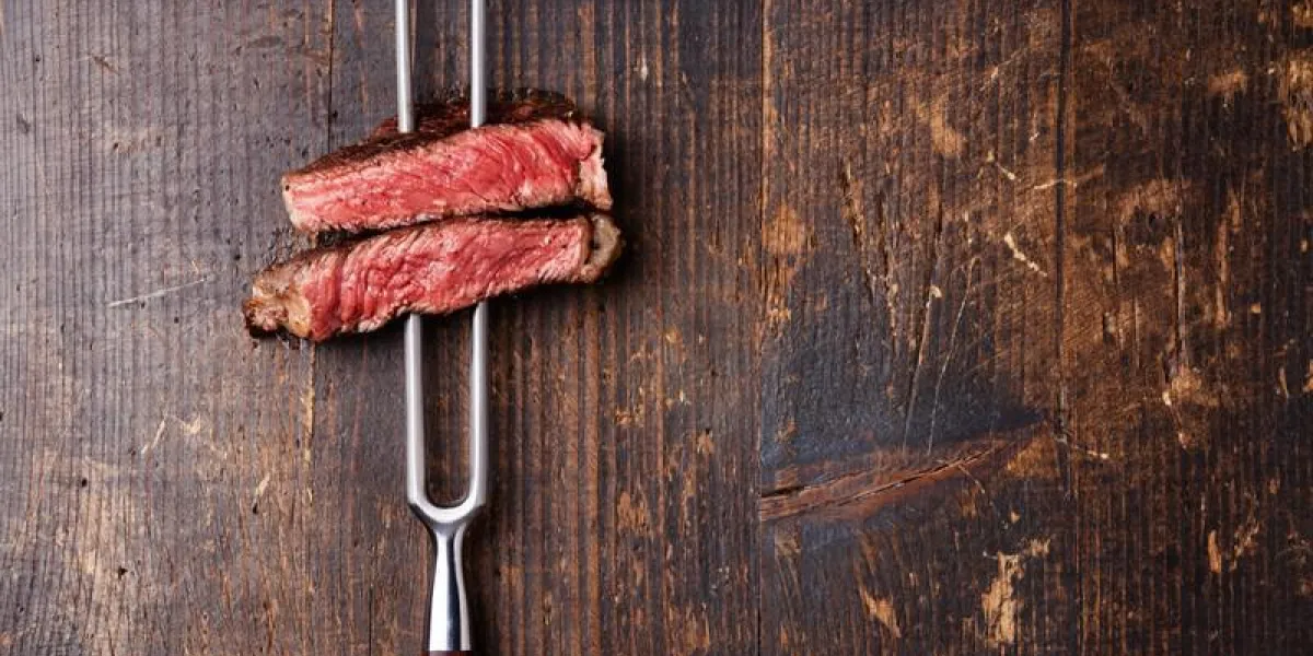 tranches de ribeye steak grillé moyen rare sur la fourchette de viande sur un fond en bois foncé