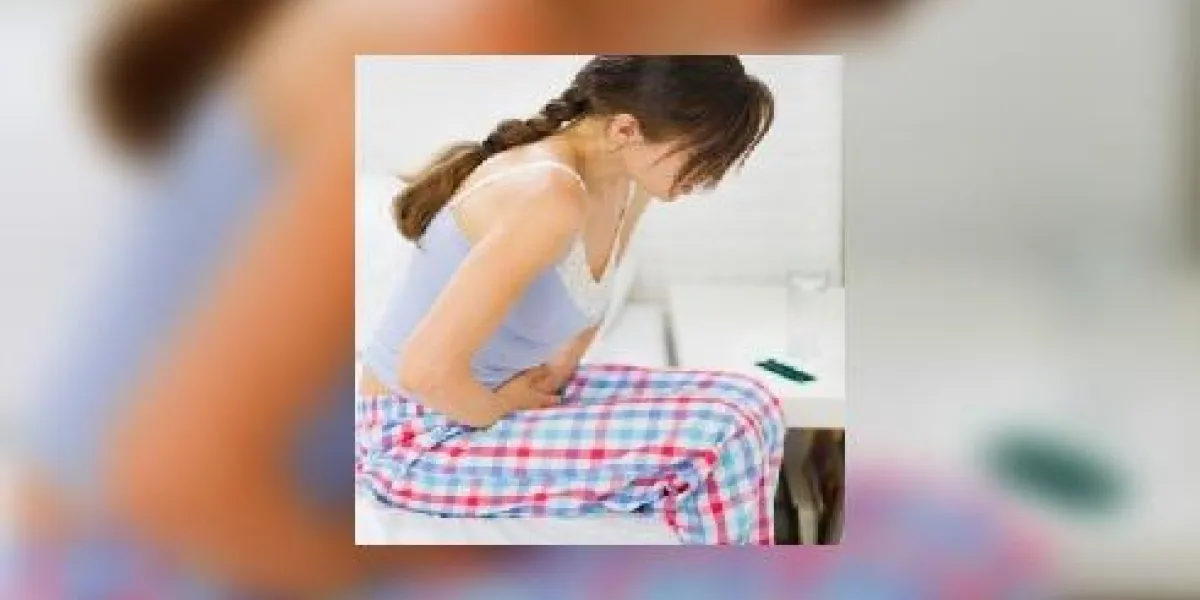 fille avec maux de ventre assis sur le lit fille avec maux de ventre assis sur le lit