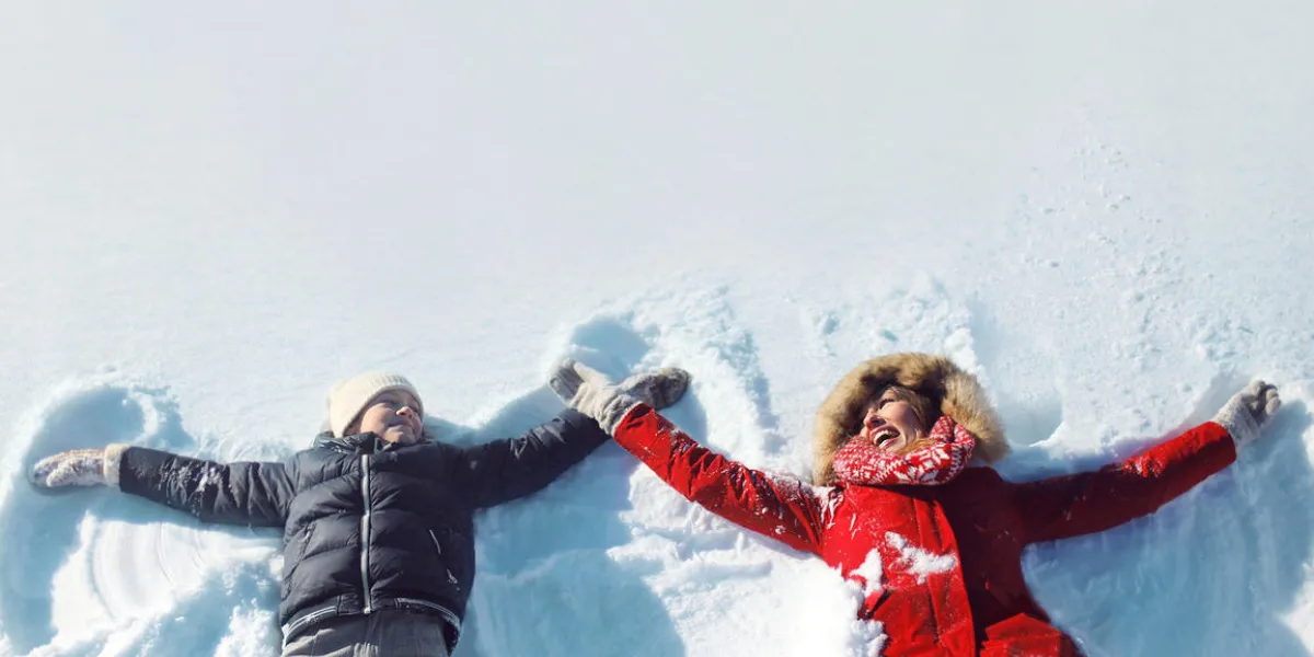heureuse mère et fils jouer et s'amuser ensemble allongé dans la neige par une journée d'hiver ensoleillée