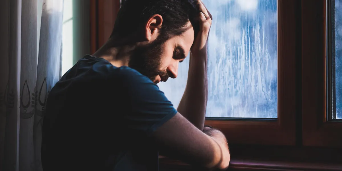 young sad mad sitting by the window in regret