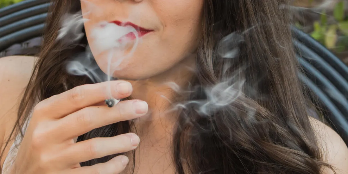 beautiful young brunette woman smoking a medical marijuana cigarette, with the smoke flowing out of her mouth beautiful young brunette woman smoking a medical marijuana cigarette, with the smoke flowing out of her mouth