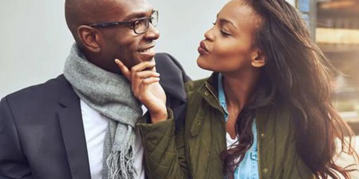 flirter jeune femme afro-américaine pinçant ses lèvres pour un baiser et caresser le visage d'un bel homme dans des verres comme ils aiment une date ensemble