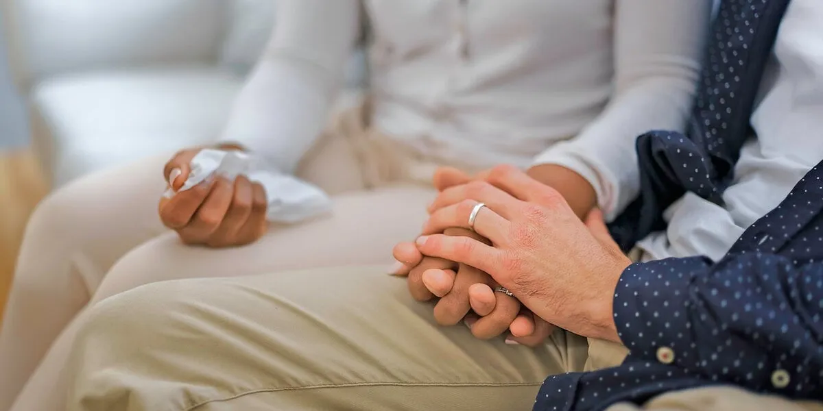 a hand holding tissu of a couple sit on sofa