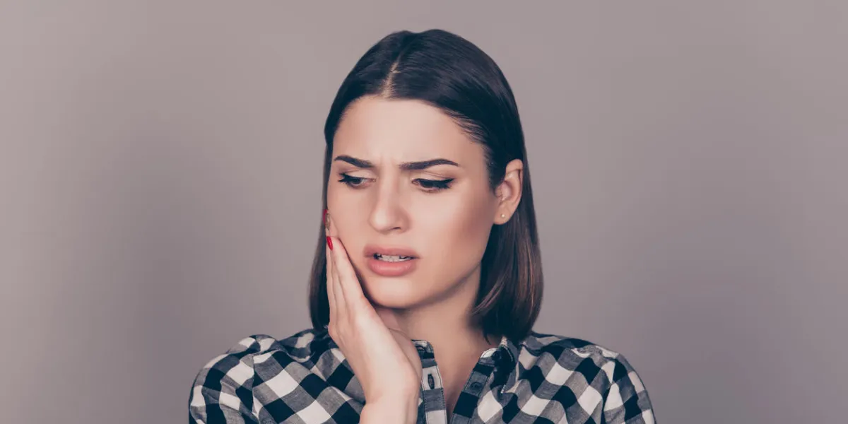 a horizontal photo of a young worried woman in checkered shirt suffering from strong toothache and touching her cheek a horizontal photo of a young worried woman in checkered shirt suffering from strong toothache and touching her cheek