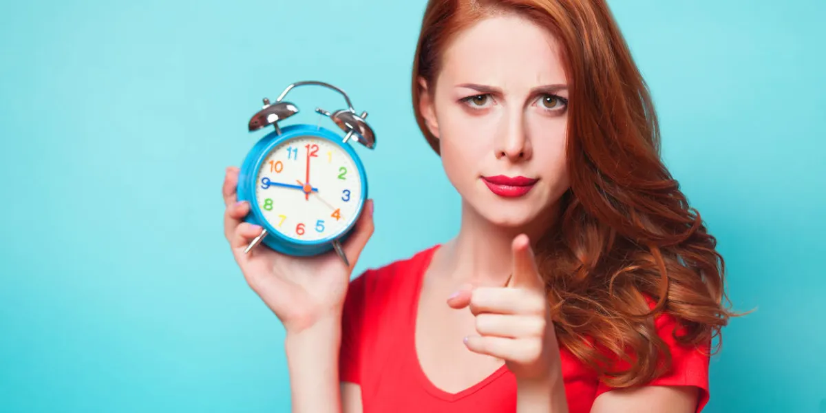 redhead girl with alarm clock on blue background