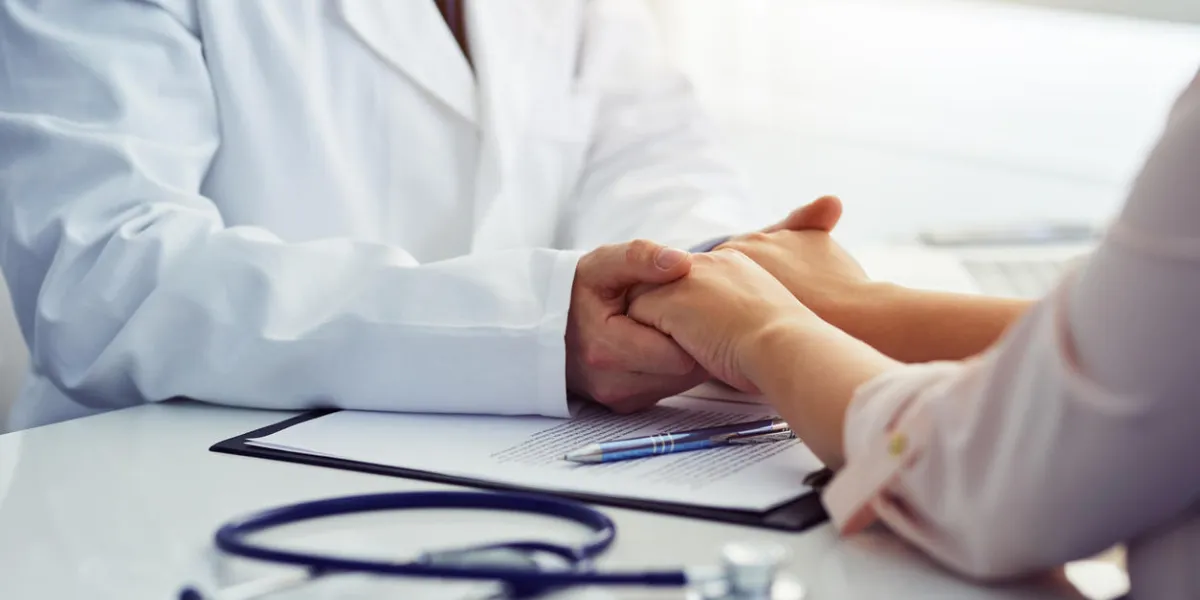 friendly male doctor reassuring the patient and holding his hands in the office friendly male doctor reassuring the patient and holding his hands in the office