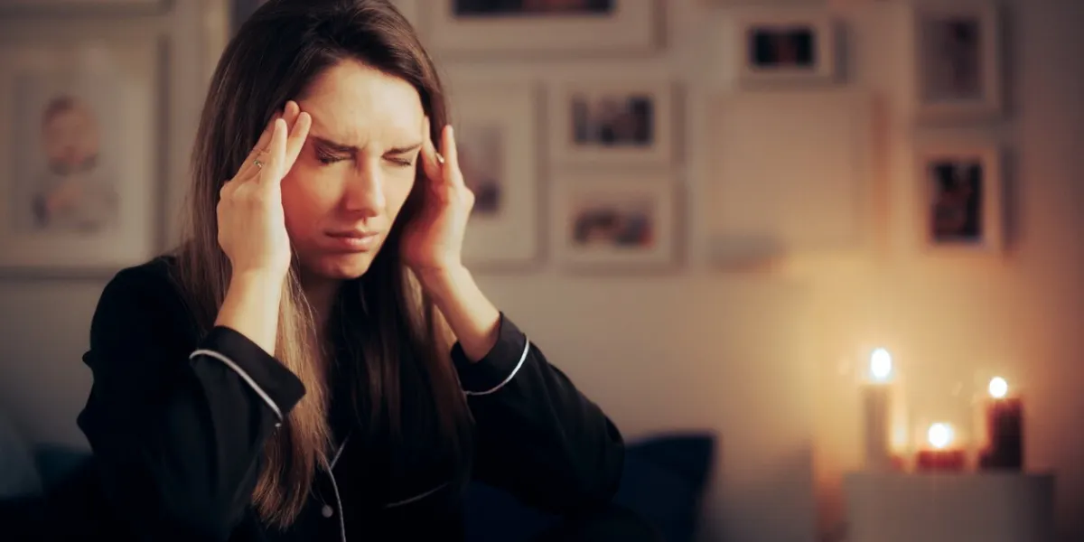 stressed woman suffering a migraine at night before going to sleep