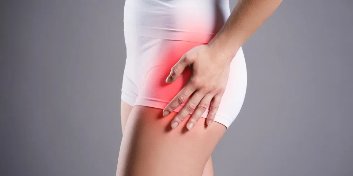 woman with pain in thigh on gray background, studio shot