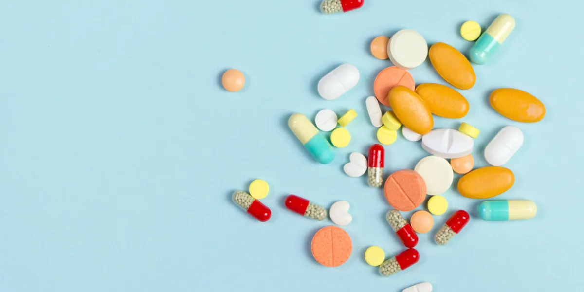 assorted pharmaceutical medicine pills, tablets and capsules over blue background