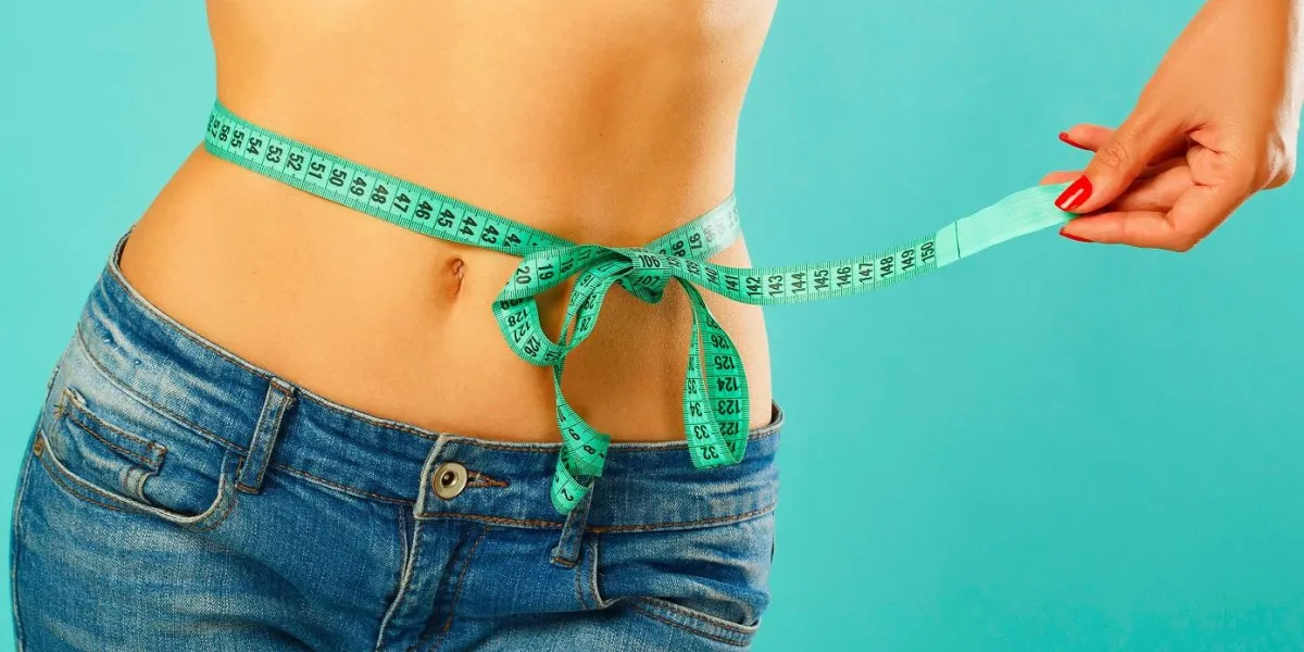 woman measuring her waist over white background wellness concept close up woman measuring her waist over white background wellness concept close up
