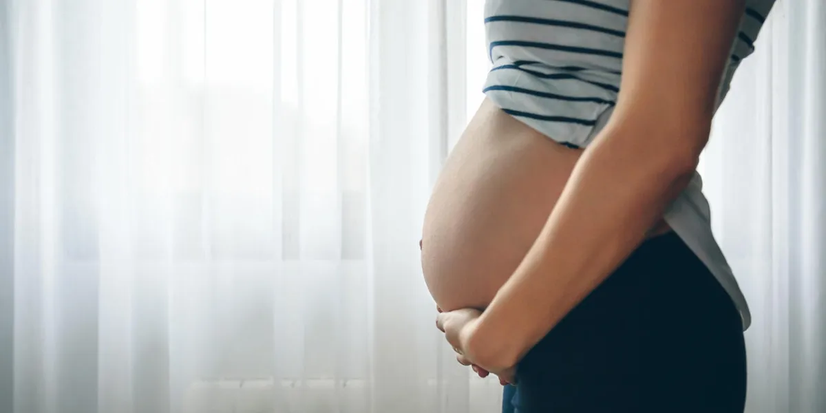 unrecognizable pregnant woman holding her tummy in the bedroom unrecognizable pregnant woman holding her tummy in the bedroom