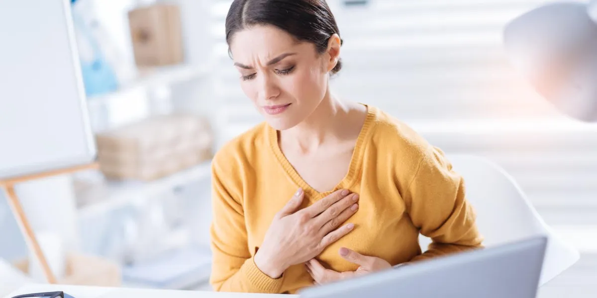 heart aching young tired overworking woman experiencing ache in a heart while sitting at the table in her big office absolutely alone heart aching young tired overworking woman experiencing ache in a heart while sitting at the table in her big office absolutely alone