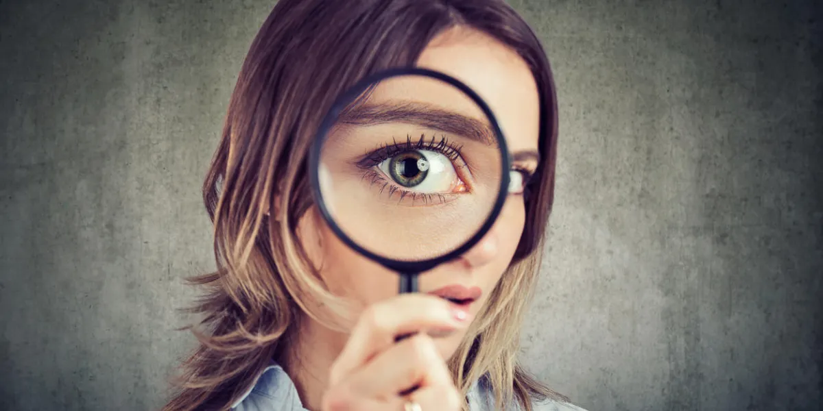 curious young woman looking through a magnifying glass curious young woman looking through a magnifying glass