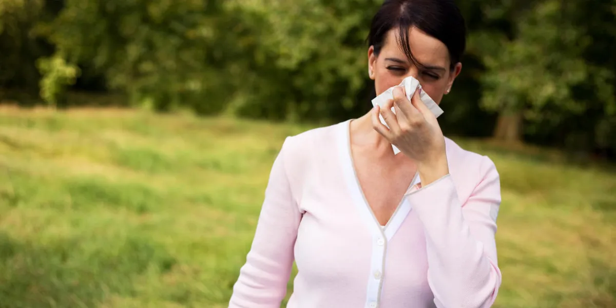 young woman suffering from a cold blowing her nose young woman suffering from a cold blowing her nose